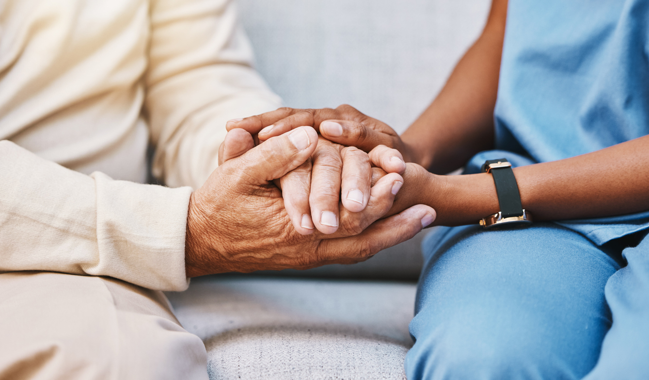 A caregiver holding the hands of an older adult